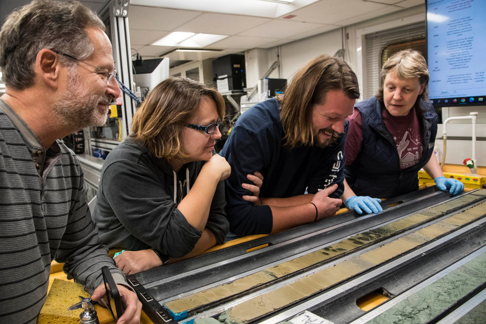 Freshly split core material with scientists making observations